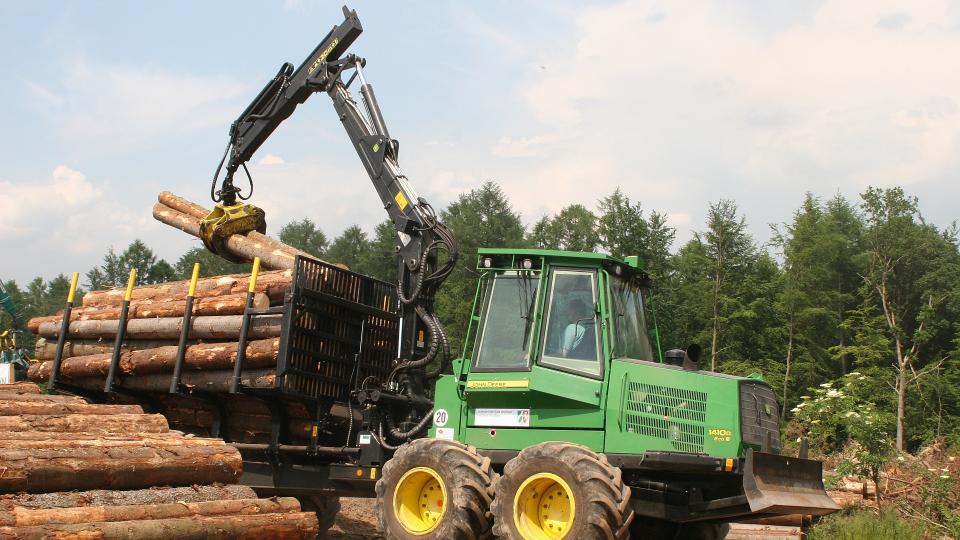 Symbolbild: Holzernte-Maschine stapelt Baumstämme