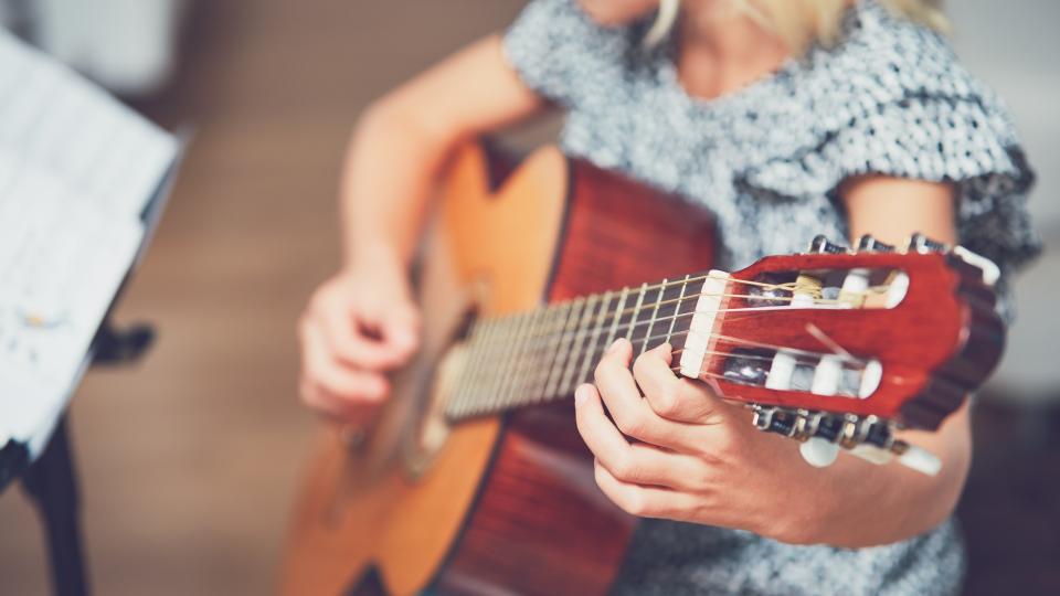 Ein Mädchen erlernt das Gitarrespielen.