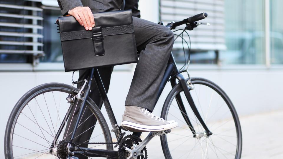 Ein Mann auf einem Fahrrad hält eine Aktentasche in der Hand.