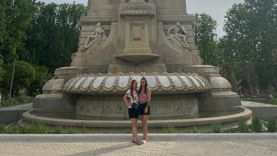 Das Bild zeigt zwei Auszubildende vor eine großen Statue im Retiro-Park in Madrid. 