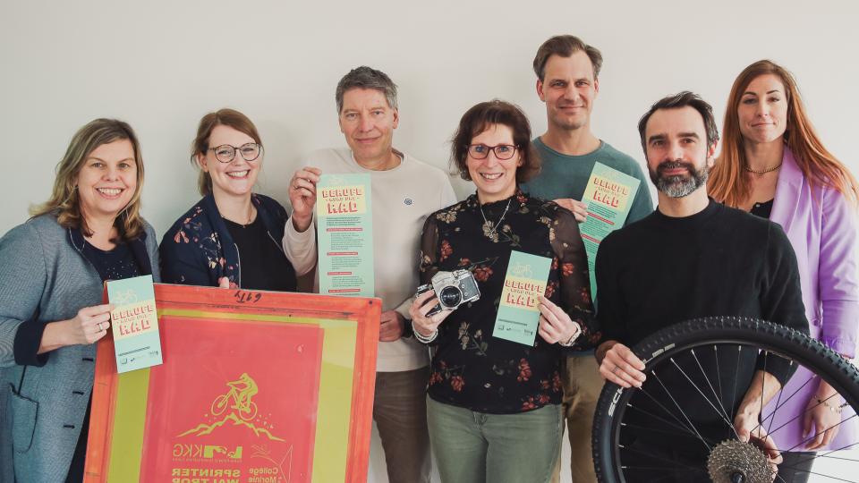 Abgebildet sind mehrere Personen, die für ein Bild posieren. Sie halten jeweils einen Flyer in den Händen und ein Mann trägt einen Fahrradreifen.