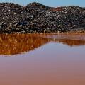 Abfälle einer Mine hinter rostfarbenem Regenwasser.