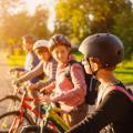 Vier Schulkinder stehen nebeneinander mit ihren Fahrrädern in einem Park. 
